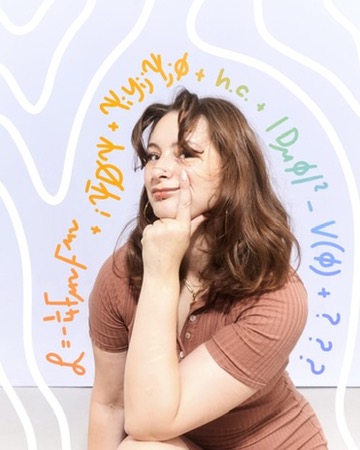 A photo of a white woman crouching with her hand on her chin, and the standard model lagrangian equation in the air around her.